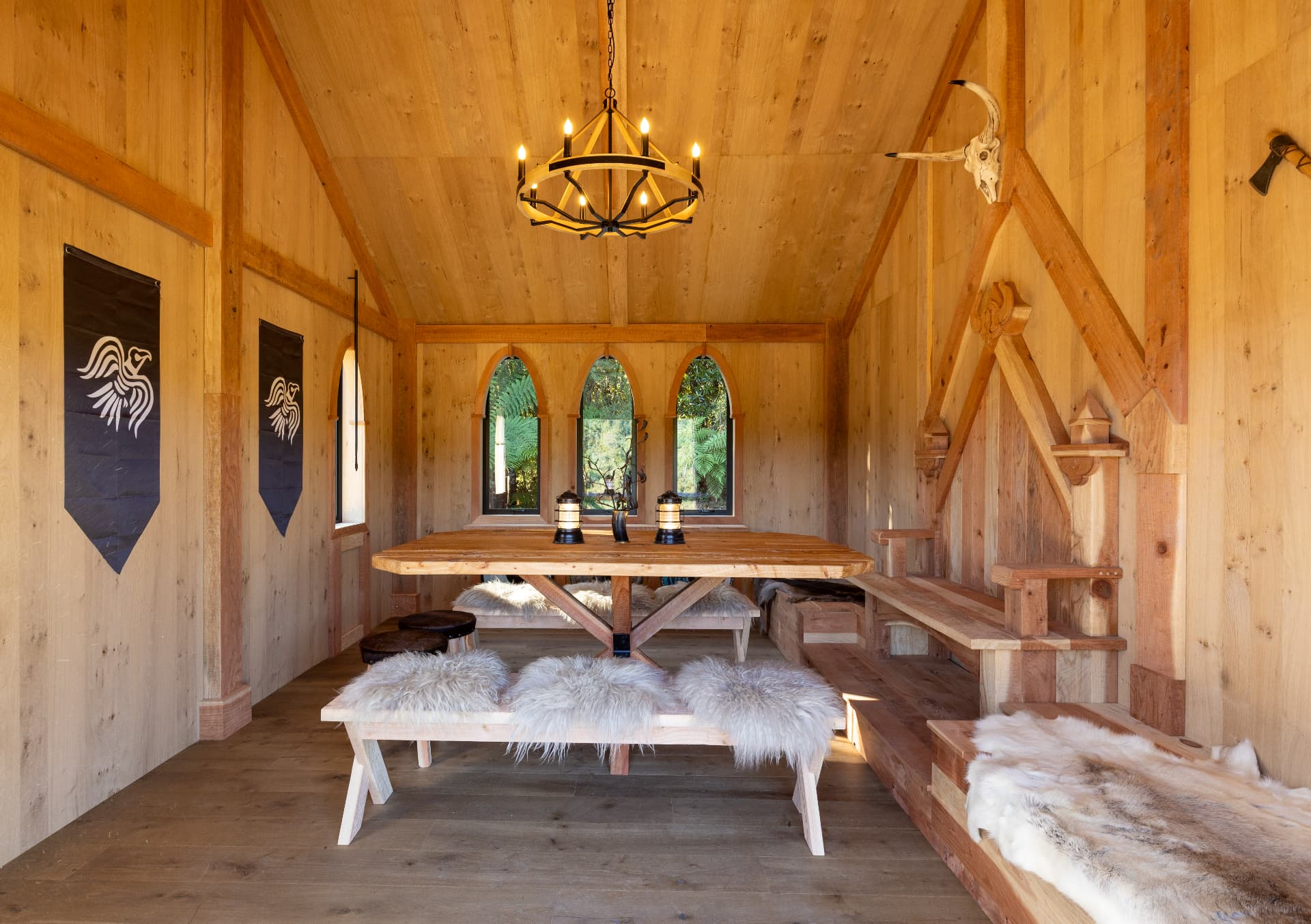 The Great Hall with a long timber table, sheepskin-covered benches and warm lantern light