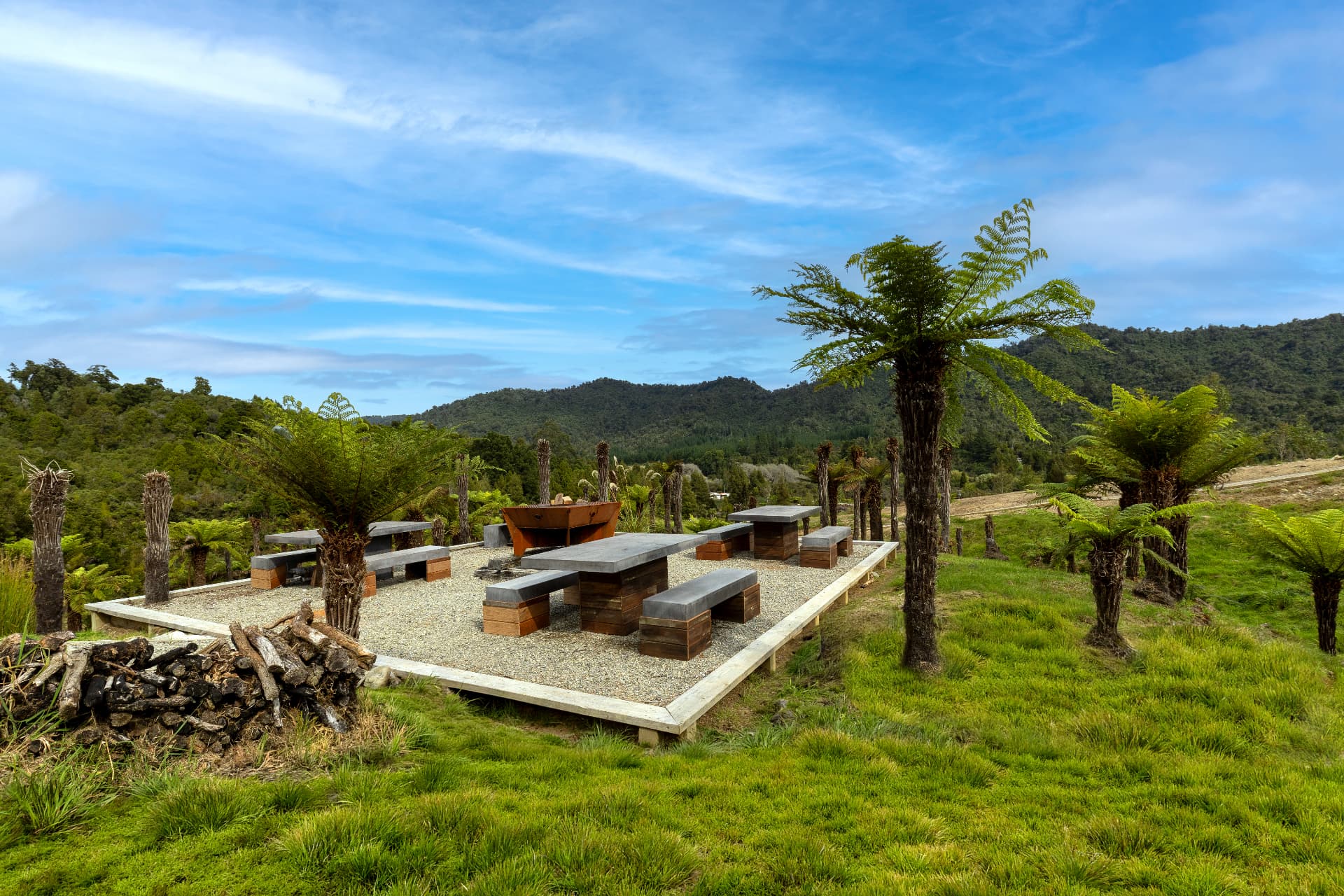 Viking Village barrel cabins and fire pit set among tree ferns beneath the Kaiata ranges