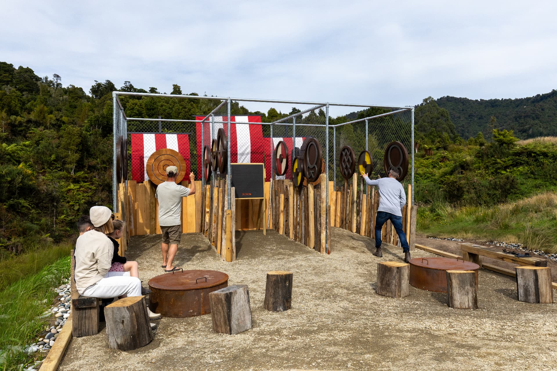 Caged axe throwing range with timber targets set against native bush