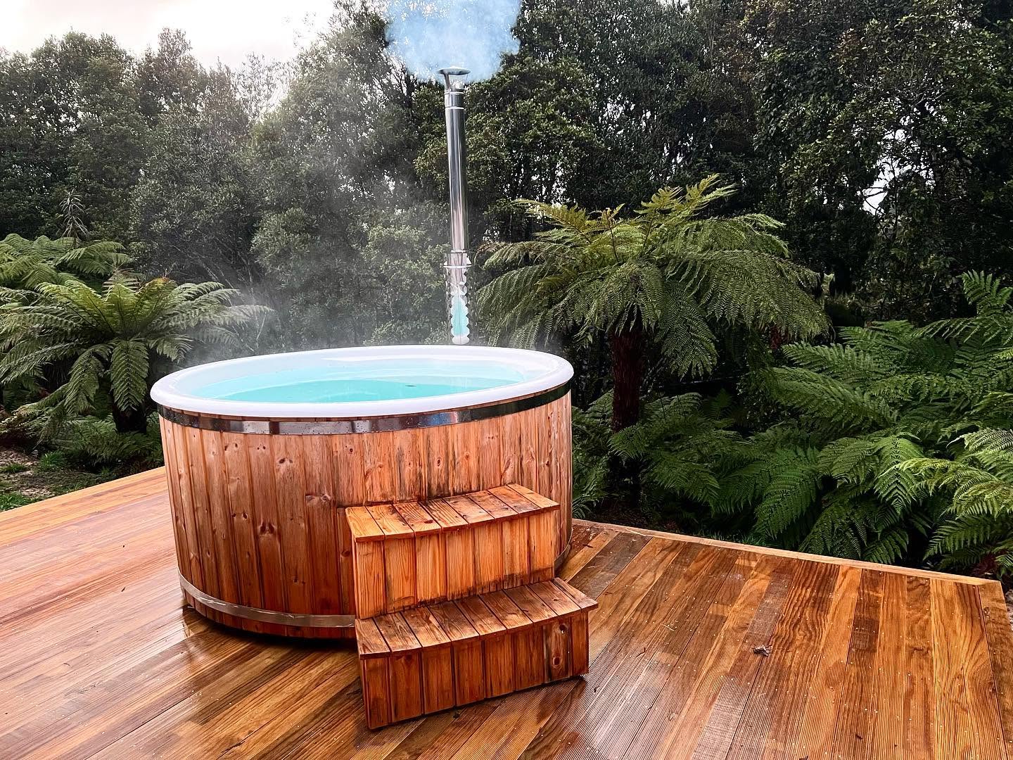 Steaming outdoor spa on a timber deck looking out to the Kaiata ranges